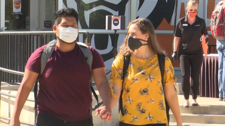 students hold hands wearing face masks
