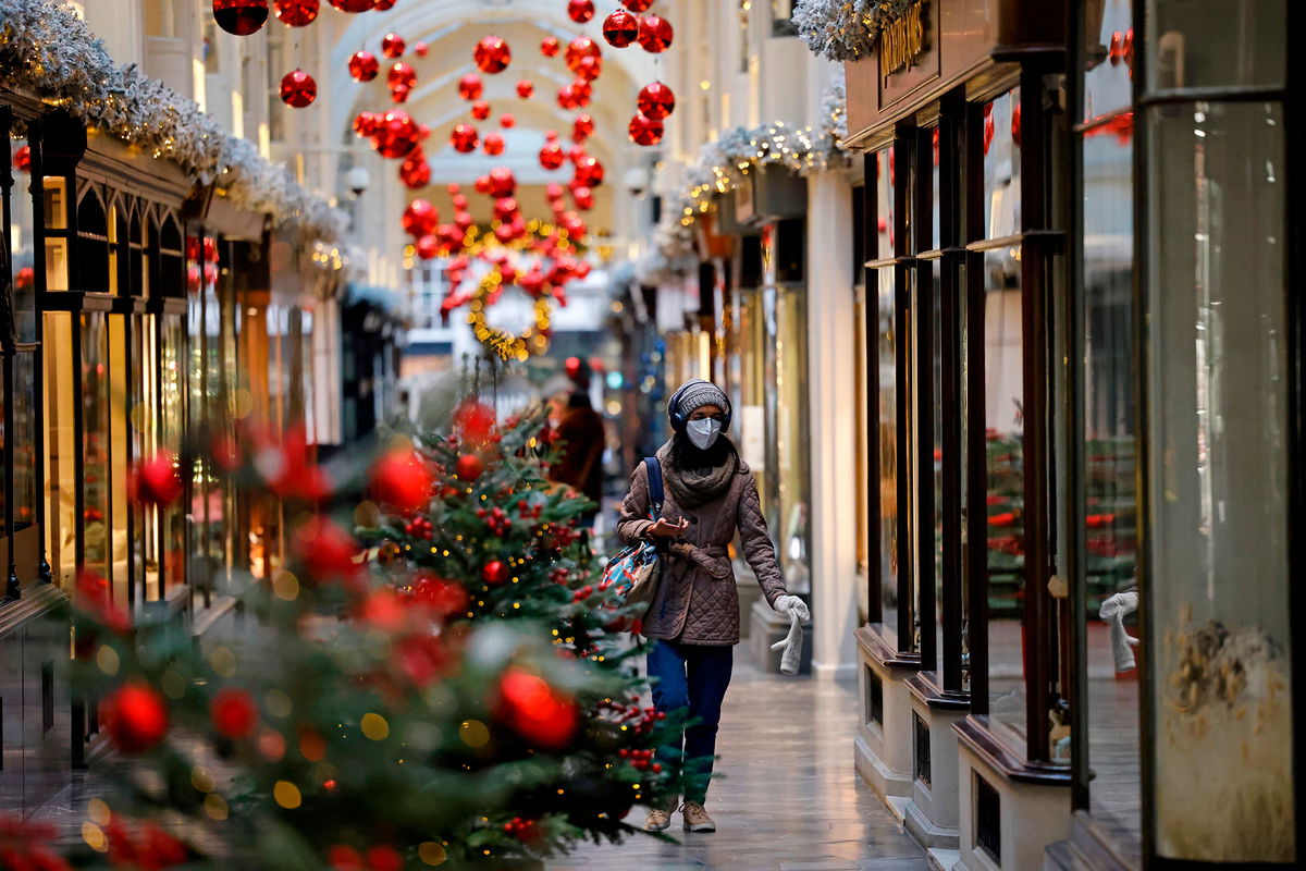 A pedestrian wearing a protective face covering to combat the spread of the coronavirus, walks past Christmas-themed window displays inside Burlington Arcade in central London on November 27, 2020, as life under a second lockdown continues in England. - England will return to a regional tiered system when the national stay-at-home order ends on December 2, and 23.3 million residents in the worst-hit areas are set to enter the