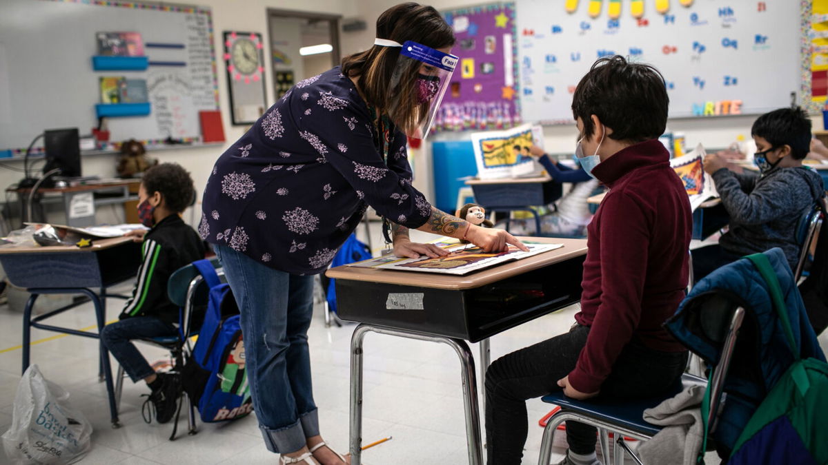 STAMFORD, CONNECTICUT - SEPTEMBER 16: Teacher Elizabeth DeSantis, wearing a mask and face shield, helps a first grader during reading class at Stark Elementary School on September 16, 2020 in Stamford, Connecticut. Most students at Stamford Public Schools are taking part in a hybrid education model, where they attend in-school classes every other day and distance learn the rest. About 20 percent of students in the school district, however, are enrolled in the distance learning option due to coronavirus concerns. (Photo by John Moore/Getty Images)