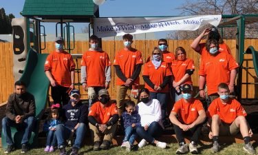 Gutierrez family sits with Home Depot volunteers in front of new playset