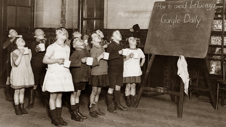 Little schoolchildren gargling their throats as a precaution against the Influenza epidemic. England. Photograph. Around 1935.
