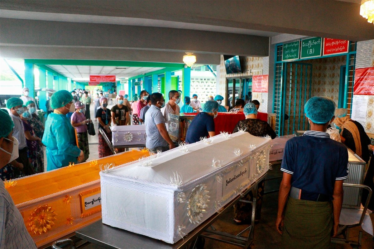 <i>AP</i><br/>People wearing face masks wait while caskets with bodies are queued outside a crematorium at the Yay Way cemetery in Yangon