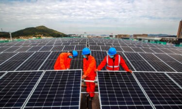 Workers install solar panels on the roof of a fish processing plant in China's Zhejiang Province in November.