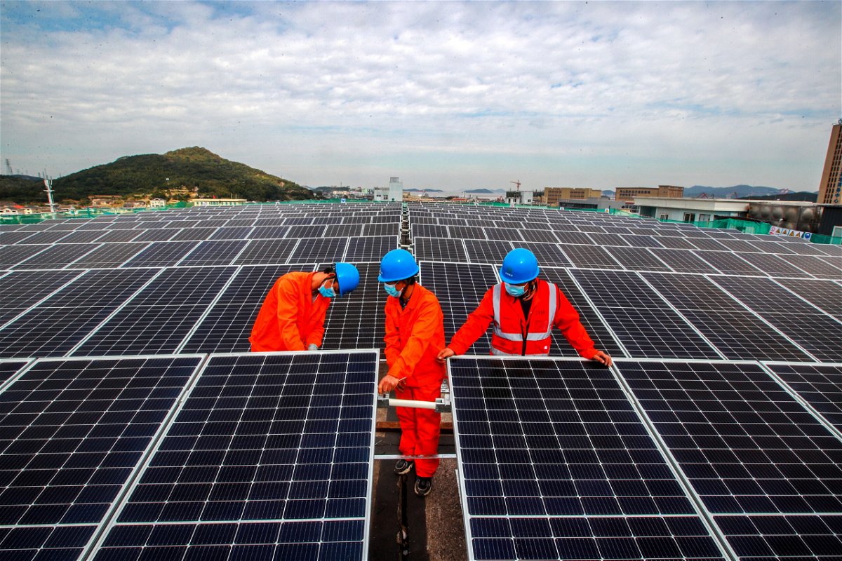 <i>Yao Feng/VCG/Visual China Group/Getty Images</i><br/>Workers install solar panels on the roof of a fish processing plant in China's Zhejiang Province in November.