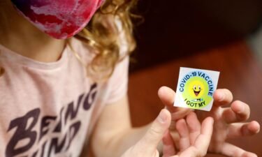 A 7 year-old child holds a sticker she received after getting the Pfizer-BioNTech Covid-19 vaccine at the Child Health Associates office in Novi