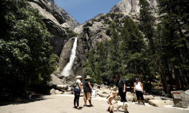 Visitors admire the view of Yosemite Falls in the distance. California's Yosemite National Park is so popular during peak summer season that it's now testing a pilot program for campers: A winter lottery in which winners get a chance to make early reservations.