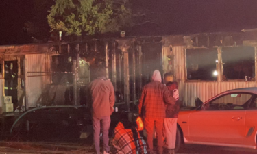 A Chubbuck family looks on as firefighters try to put out hot spots in their mobile home