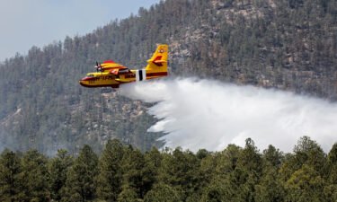 Officials urge residents in northern New Mexico to leave ahead of a rapidly growing blaze. An aircraft battles the Hermits Peak and Calf Canyon Fires in the Santa Fe National Forest in New Mexico on Thursday
