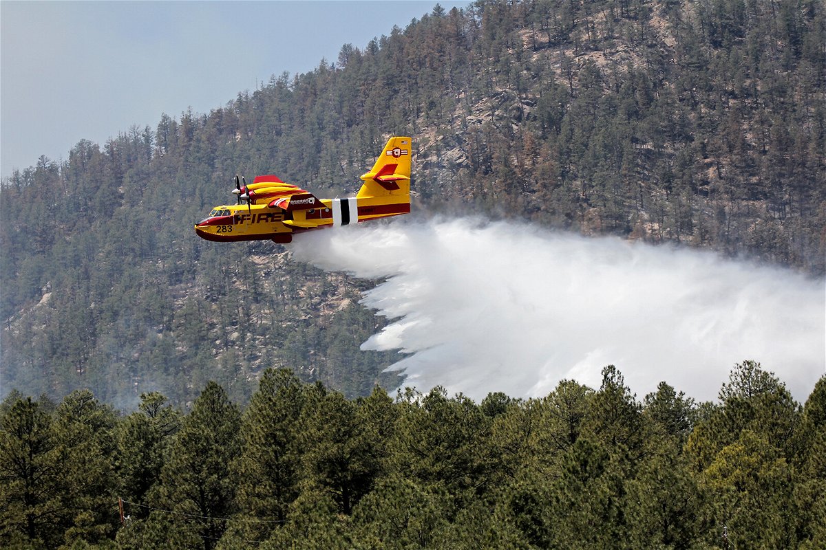 <i>J. Michael Johnson/AP</i><br/>Officials urge residents in northern New Mexico to leave ahead of a rapidly growing blaze. An aircraft battles the Hermits Peak and Calf Canyon Fires in the Santa Fe National Forest in New Mexico on Thursday