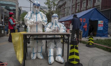 Health workers wait to give local residents nucleic acid tests to detect Covid-19 at a makeshift testing site in Chaoyang District on April 25