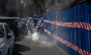 Workers in protective suits disinfect an area outside a barricaded community that was locked down for health monitoring after recent cases of Covid-19 were found in the area on March 28