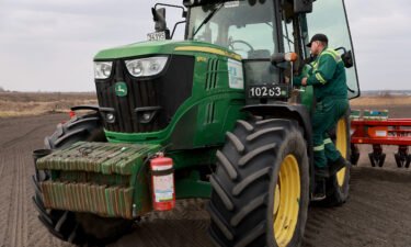 Ukrainian farmer Morda Vasyl steps into the cab of a John Deere tractor.