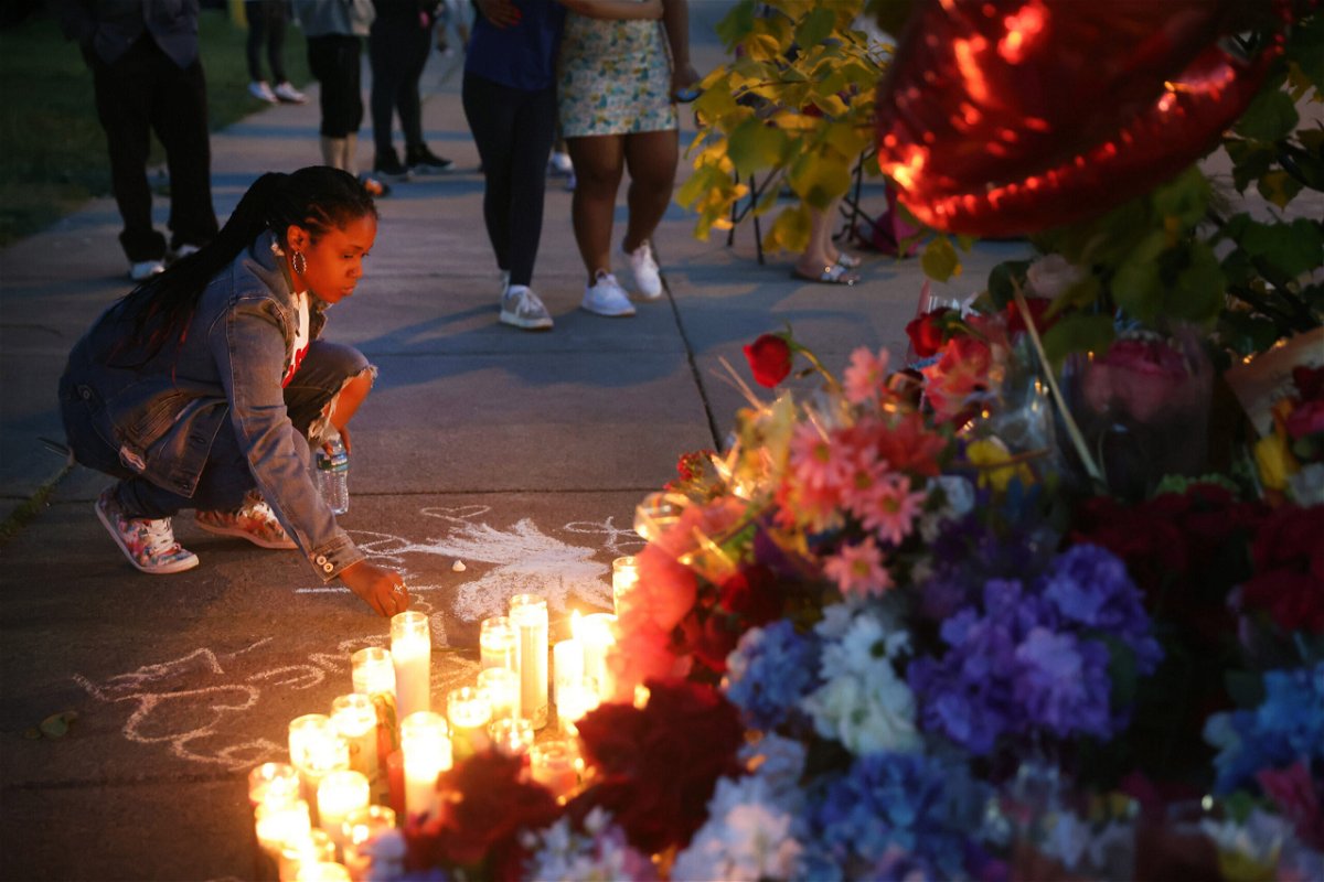 <i>Scott Olson/Getty Images</i><br/>A woman chalks a message on May 16 at a makeshift memorial outside of a Tops grocery store in Buffalo.