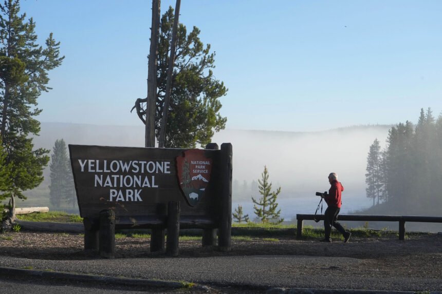 A man takes a picture at the south entrance of Yellowstone National Park