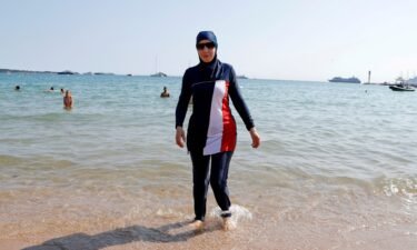 A woman wearing a burkini walks on a beach in Cannes