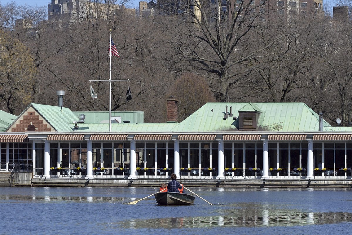 <i>Anthony Behar/Sipa USA/AP</i><br/>A woman rows a boat on The Lake in Central Park in front of The Loeb Boathouse in New York in March 2021. Central Park's Loeb Boathouse will permanently close this fall amid rising costs.