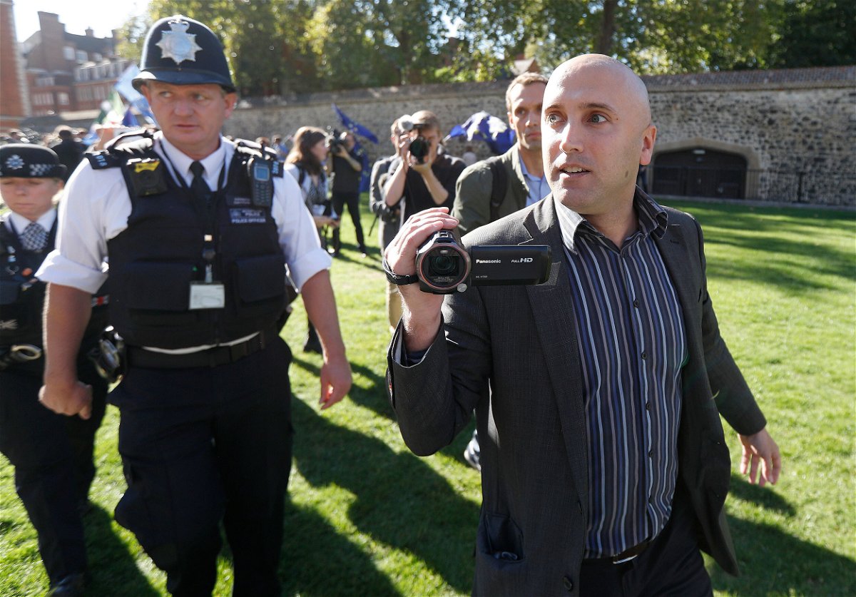 <i>Peter Nicholls/Reuters</i><br/>Blogger Graham Phillips is escorted away by police officers after he disrupted a press conference by Bellingcat founder Eliot Higgins