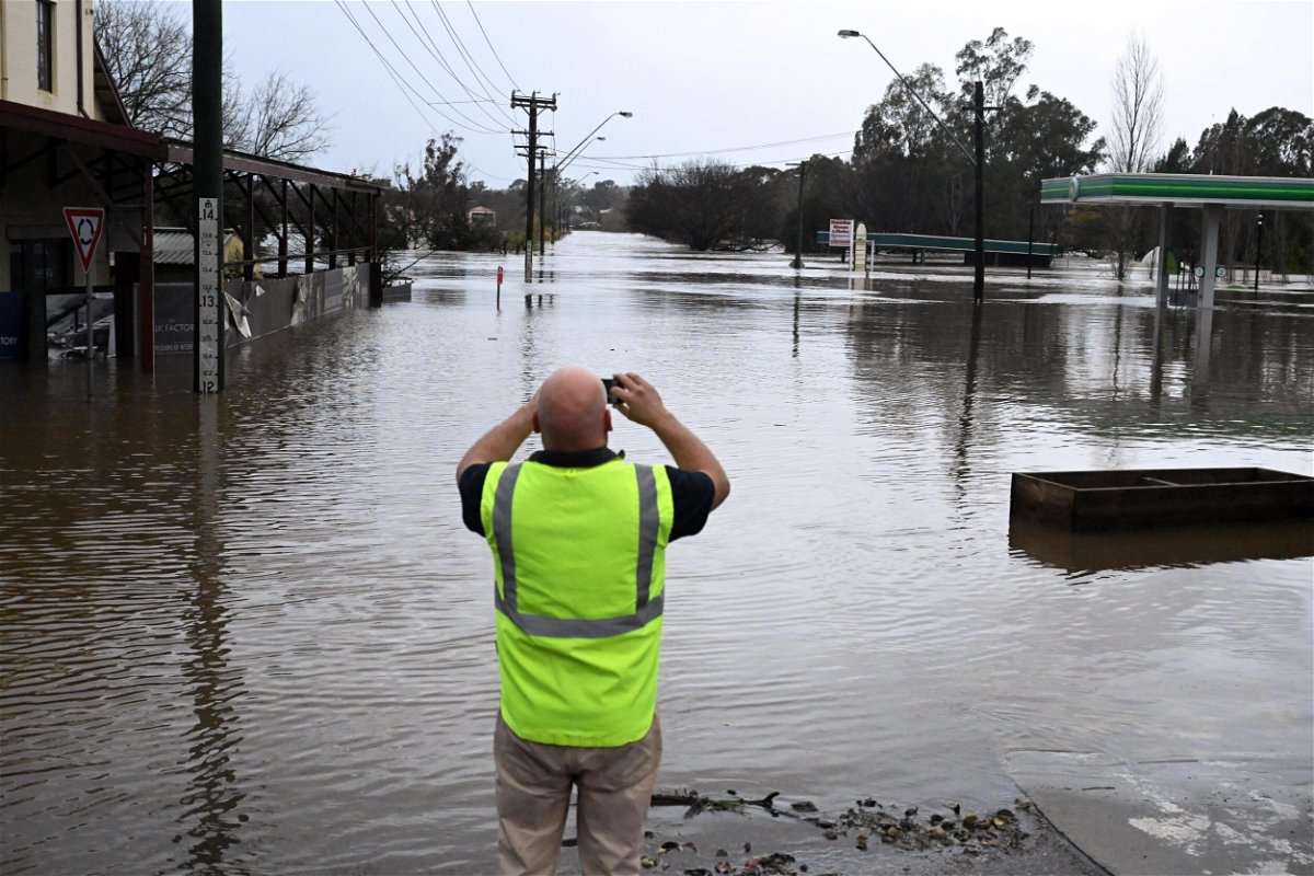 <i>Mick Tsikas/AAP Image/Reuters</i><br/>A local takes a photo of a road inundated by floodwaters in Camden in South Western Sydney