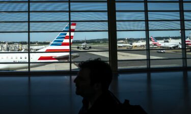 A traveler walks past American Airlines planes gated at Ronald Regan Washington National Airport on July 11 in Arlington