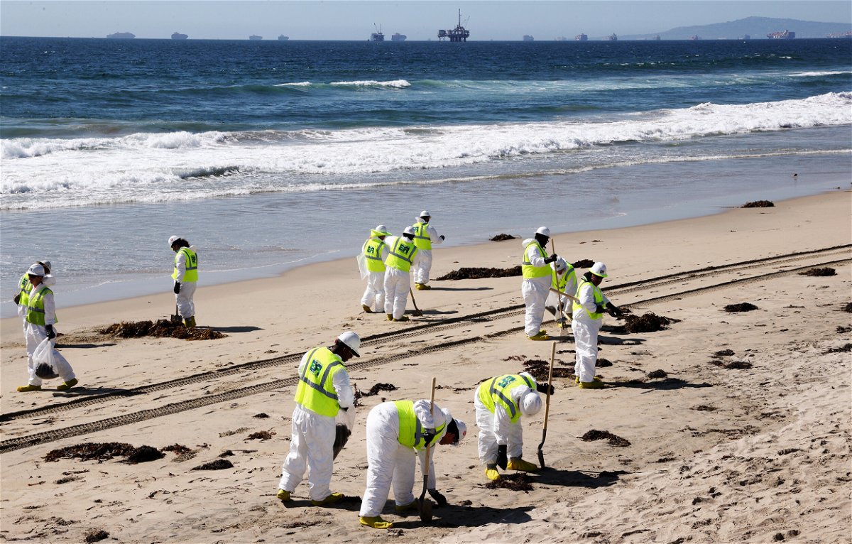 <i>Mario Tama/Getty Images/FILE</i><br/>Cleanup workers search for contaminated sand and seaweed along the mostly empty Huntington Beach