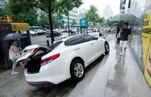 A vehicle is damaged on the sidewalk after floating in heavy rainfall in Seoul