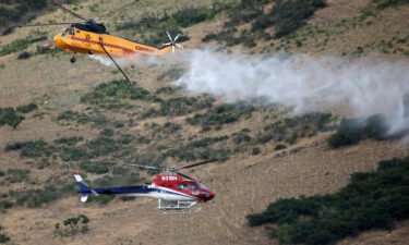 Two helicopters pass while fighting a wildfire in Springville