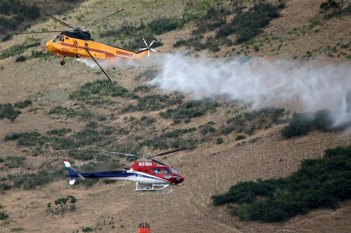 <i>Kristin Murphy/The Deseret News/AP</i><br/>Two helicopters pass while fighting a wildfire in Springville