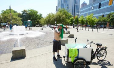 Matthew Carr dries himself after cooling off in the Salmon Street Springs fountain before returning to work cleaning up trash on his bicycle in Portland