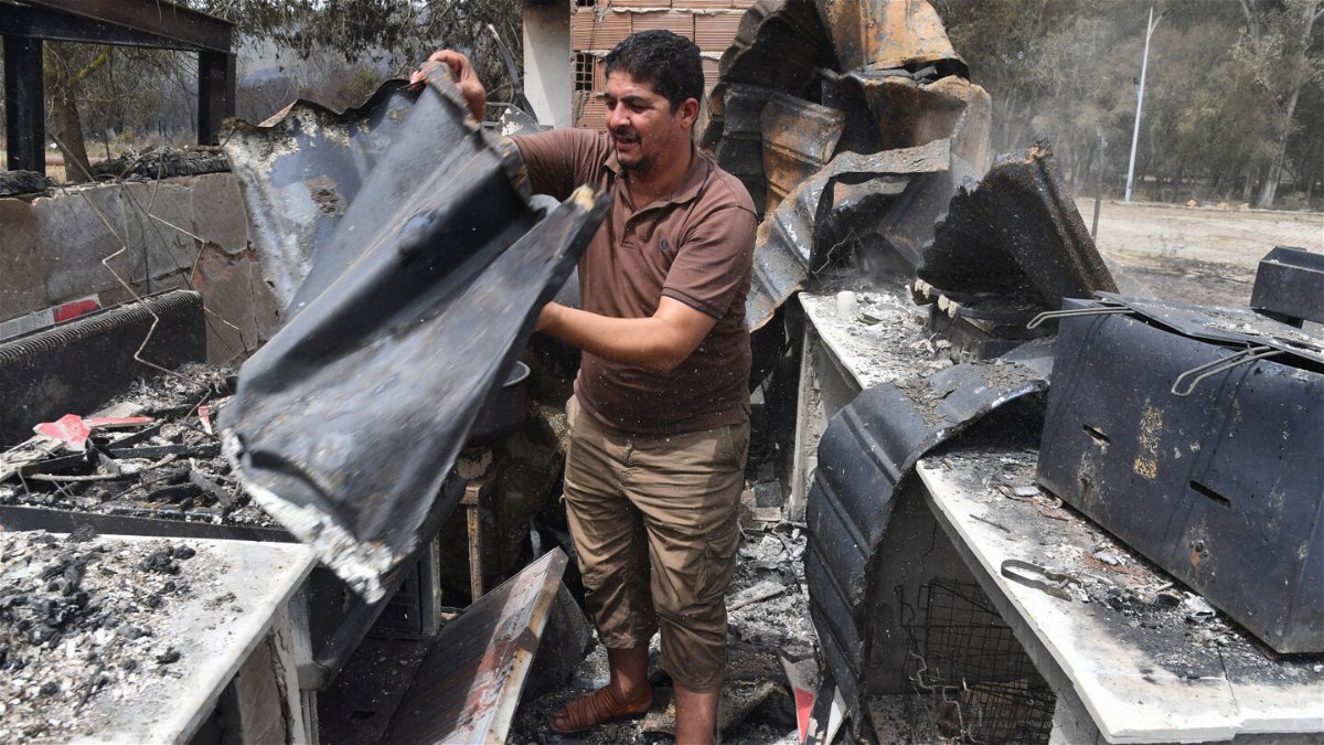 <i>RYAD KRAMDI/AFP via Getty Images</i><br/>At least 26 people have been killed and several injured in wildfires that ravaged mountainous areas in the east of Algeria. A man checks burnt objects following raging fires in Algeria's city of el-Kala on August 17.