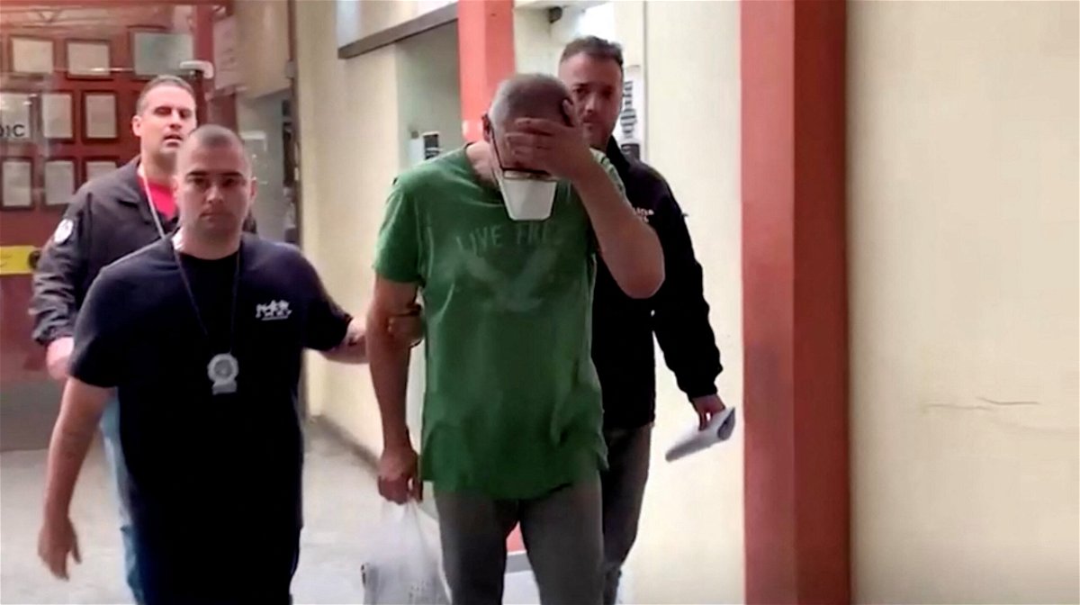 <i>Reuters</i><br/>Police officers with Uwe Herbert Hahn (second from right) following his arrest. A Brazilian Judge has ordered that German Consul Uwe Herbert Hahn should be held in custody in connection with the alleged murder of his husband in Rio de Janeiro.