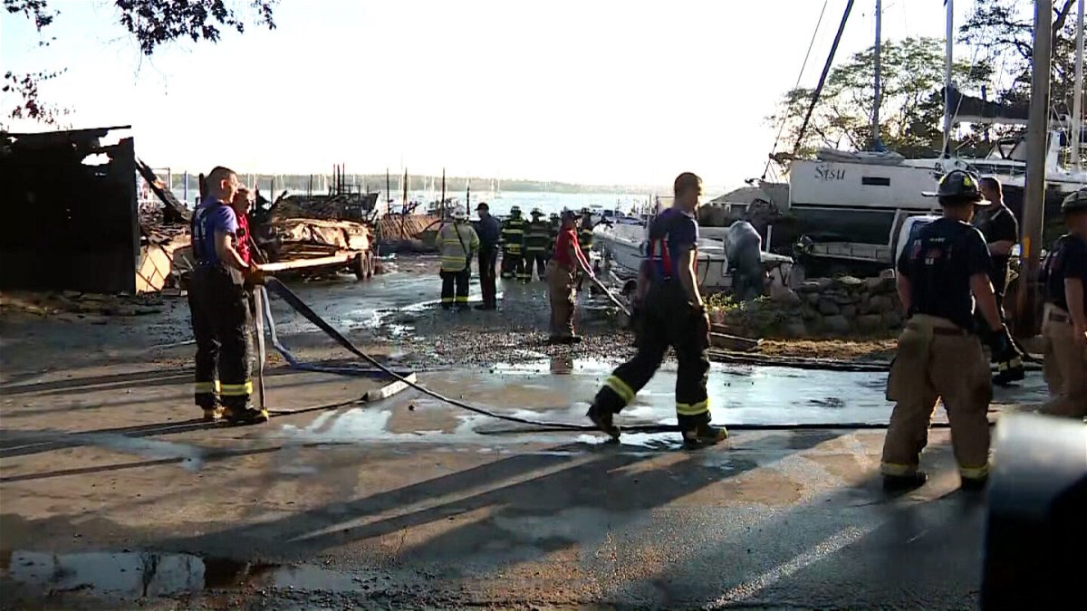 <i>WCVB</i><br/>Firefighters work at the scene of a massive boatyard fire in Mattapoisett