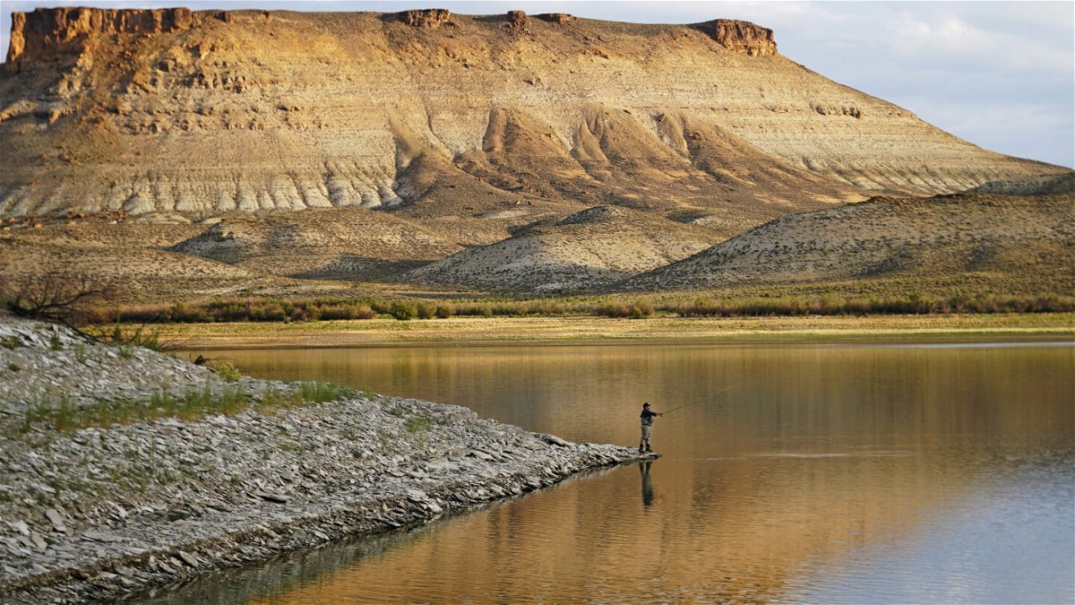 Nick Gann fishes in Firehole Canyon Friday, Aug. 5, 2022, on the far northeastern shore of Flaming Gorge Reservoir, in Wyoming. A boating and fishing paradise on the Utah-Wyoming line, Flaming Gorge is beginning to feel the effects of the two-decade megadrought gripping the southwestern U.S.