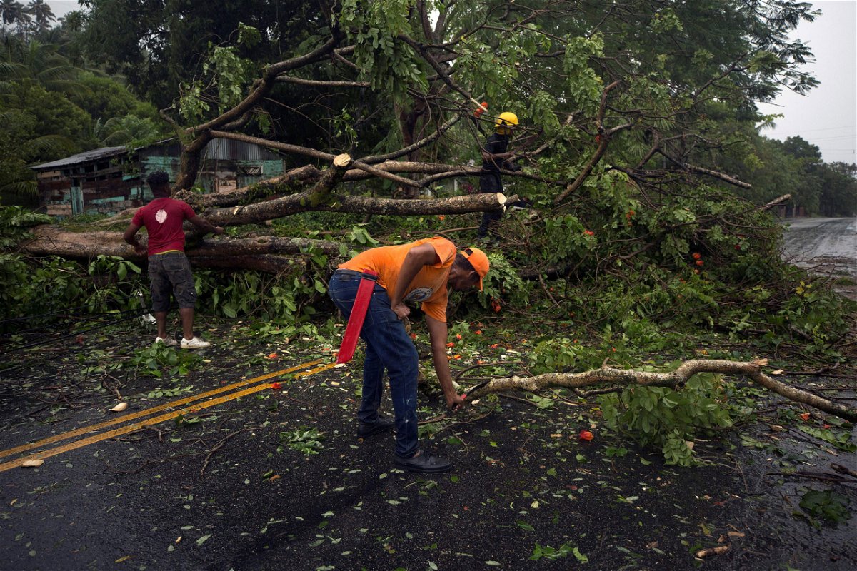 <i>Erika Santelices/AFP/Getty Images</i><br/>Civil defense personnel and firefighters are pictured here working to remove fallen trees from the highway connecting the provinces of Maria Trinidad Sanchez and Samana