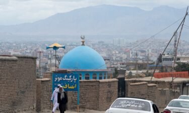 The Biden administration has set up a new fund that could eventually put billions of dollars in frozen Afghan money to use to promote economic stability. Afghan men are pictured here walking past the blue dome of a mosque a day after a blast in Kabul.