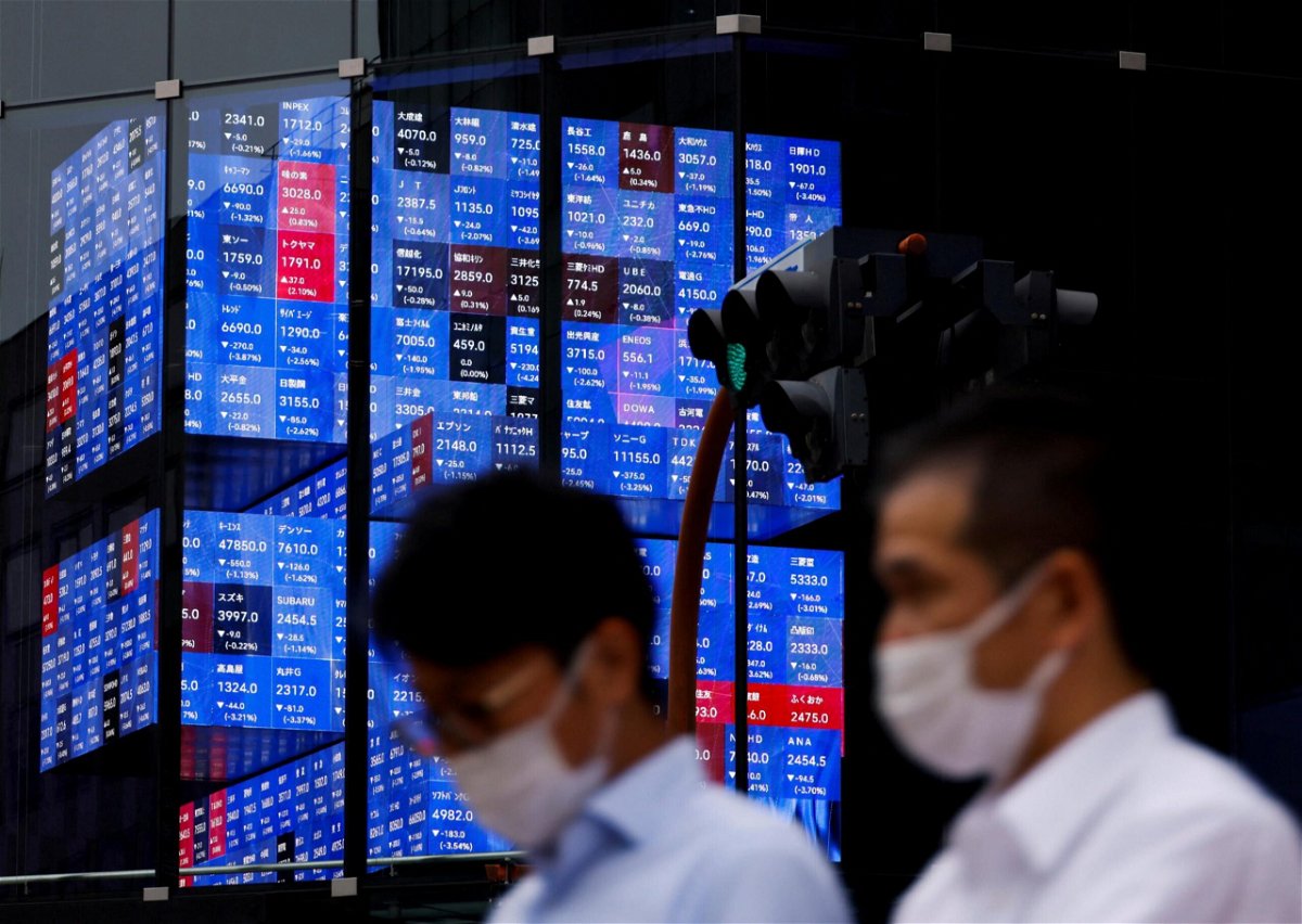 <i>Issei Kato/Reuters</i><br/>Asian markets are on track for their worst month since the pandemic began. People pass by a screen showing Japan's Nikkei share price index in Tokyo on June 14.