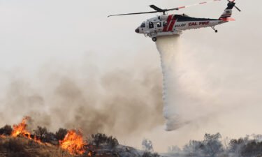 A firefighting helicopter drops water as the Fairview Fire burns on September 7 near Hemet