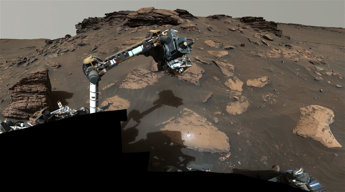 <i>NASA</i><br/>Perseverance uses its robotic arm to work around a rocky outcrop called Skinner Ridge.