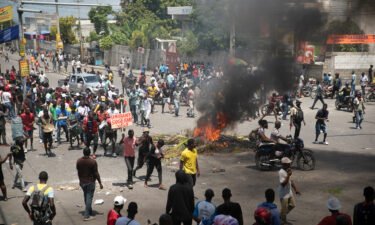 People walk around burning tires set up by protesters during a protest to demand that Haitian Prime Minister Ariel Henry step down and a call for a better quality of life