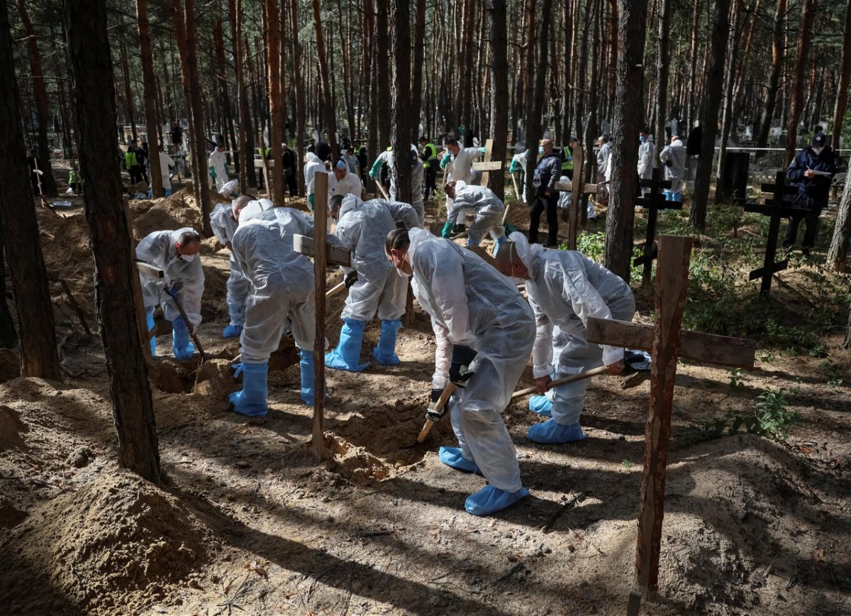 <i>Gleb Garanich/Reuters</i><br/>Members of the Ukrainian Emergency Service work at a mass burial site during an exhumation