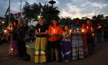 People hold candles during a vigil for the stabbing attack victims in Prince Albert