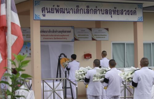 A Thai officer lays a wreath of flowers from the royal family to mourn those killed at a child care center in the country's north.
