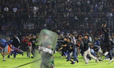 Soccer fans enter the pitch during a clash between supporters at Kanjuruhan Stadium in Malang
