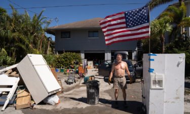 A man stands in front of a home damaged by storm surge in the wake of Hurricane Ian in Naples