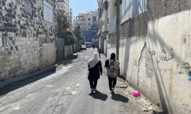 Two women walk along the narrow alleyways of the Shuafat refugee camp