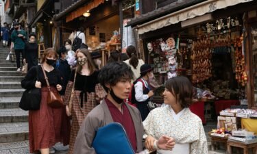 People walk down a shopping street in a touristy section of Kyoto