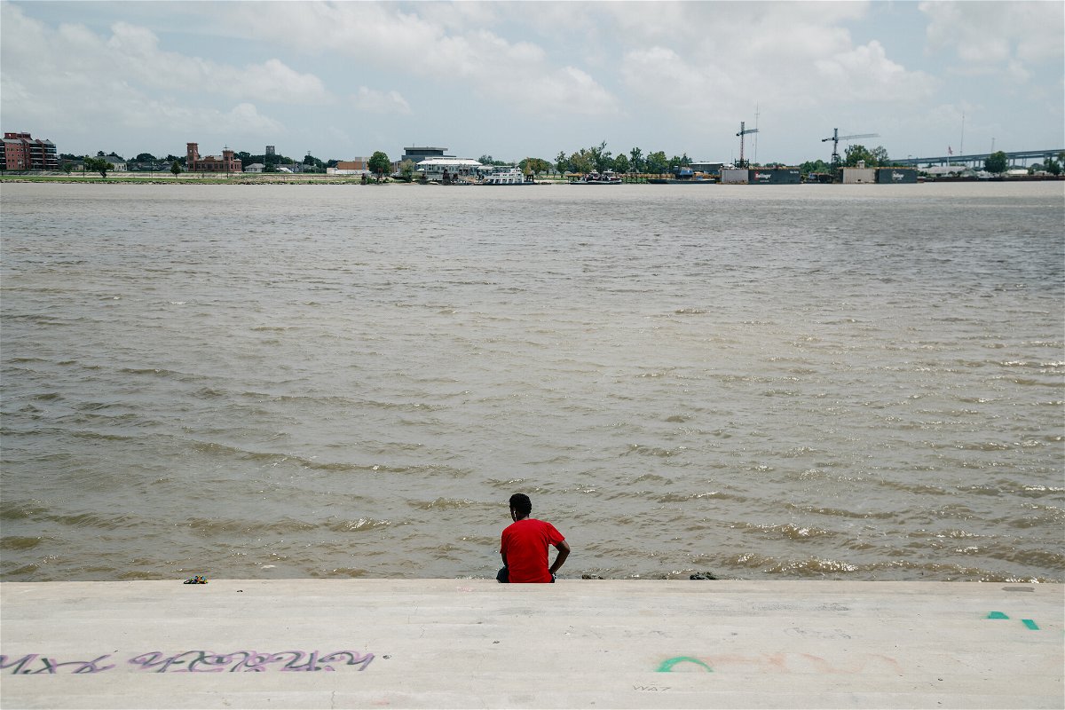 <i>Bryan Tarnowski/Bloomberg/Getty Images</i><br/>A person sits along the Mississippi River near New Orleans in August 2020.