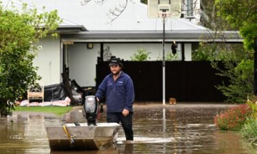 A man pushes a boat as floodwaters inundate a Victorian residential area in Rochester