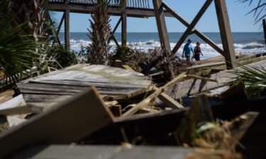 A couple walks past damage from Hurricane Ian on Litchfield Beach