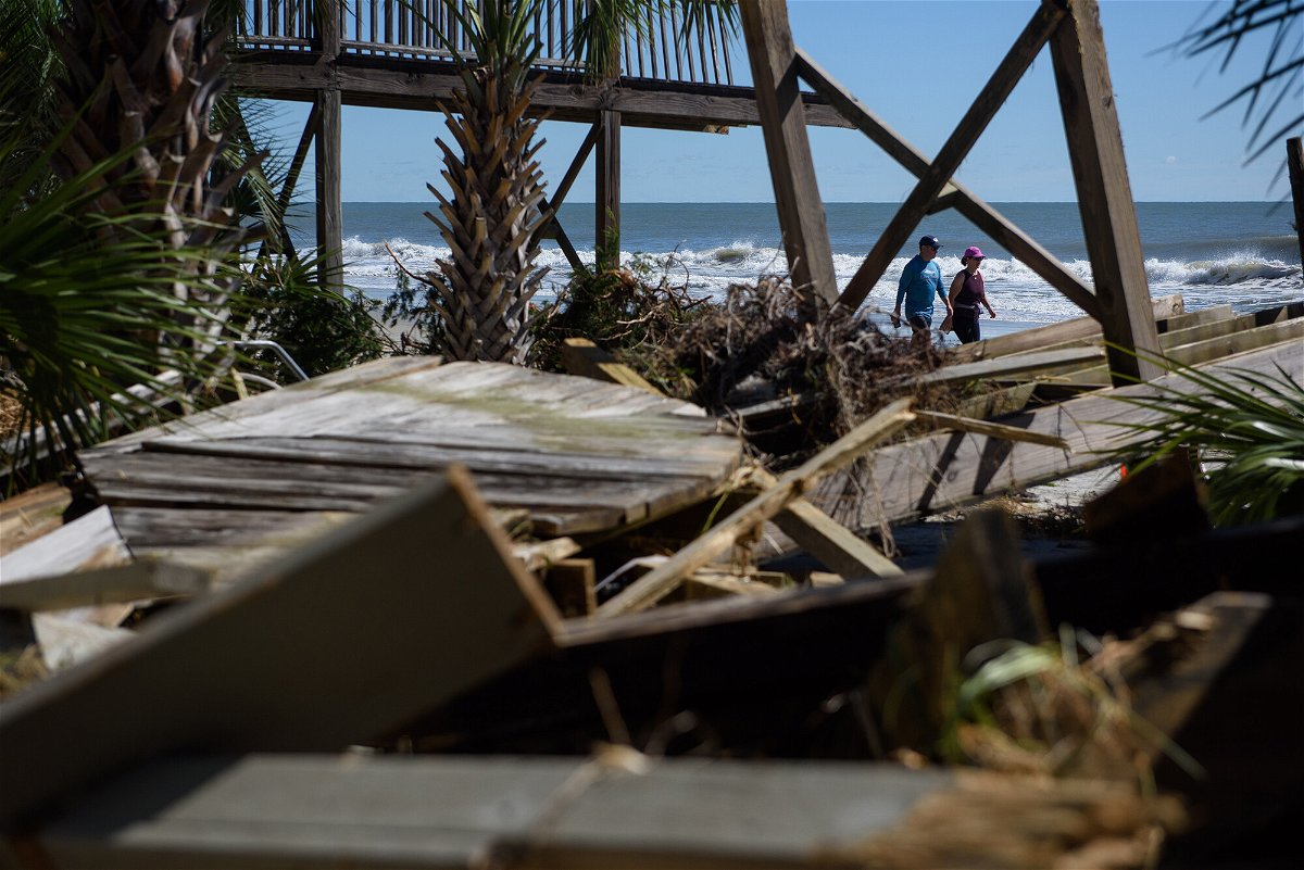 <i>Melissa Sue Gerrits/The Washington Post/Getty Images</i><br/>A couple walks past damage from Hurricane Ian on Litchfield Beach