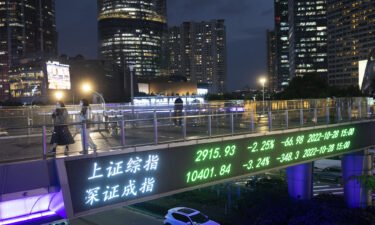 People walk on a pedestrian bridge which displays the numbers for the Shanghai Shenzhen stock indexes on October 28